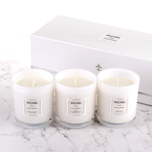Load image into Gallery viewer, Three white candles with the brand name Michel on them, displayed in front of a white box with the Michel logo.