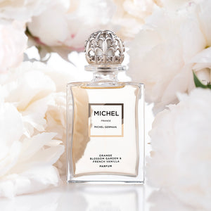Michel Germain orange vanilla perfume bottle with soft white floral background