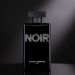 Front view of Noir cologne bottle illuminated dramatically under spotlight