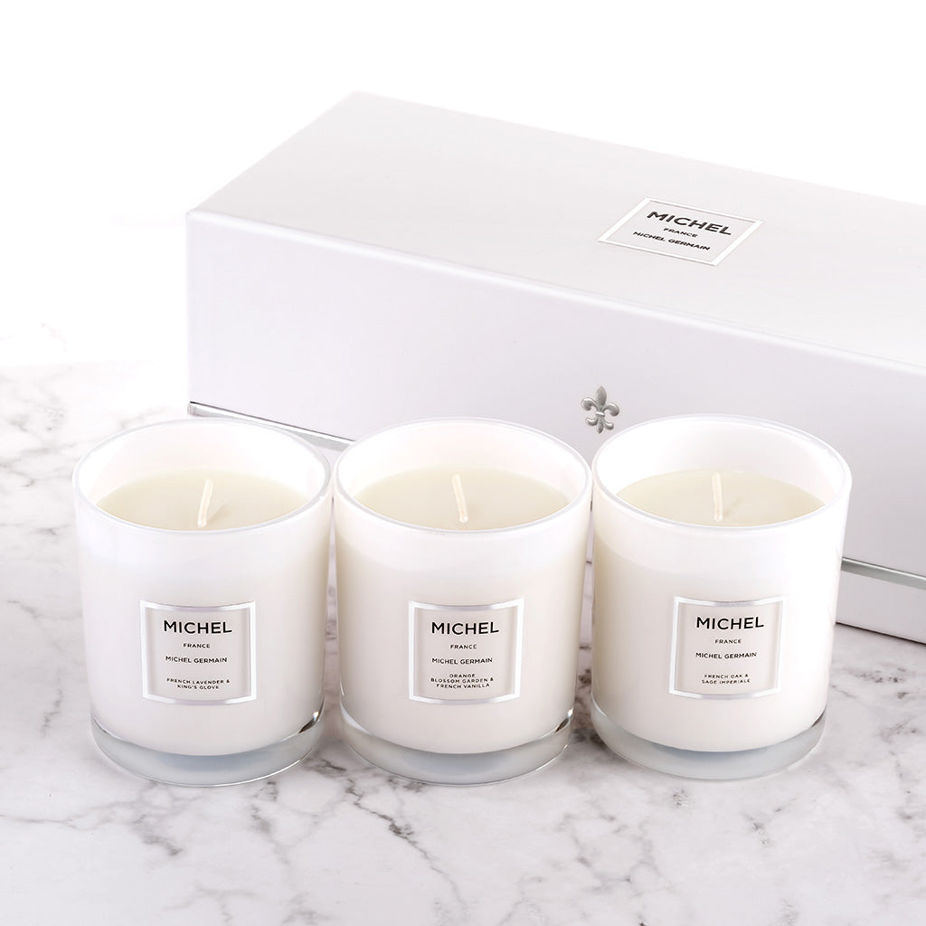 Three white candles with the brand name Michel on them, displayed in front of a white box with the Michel logo.